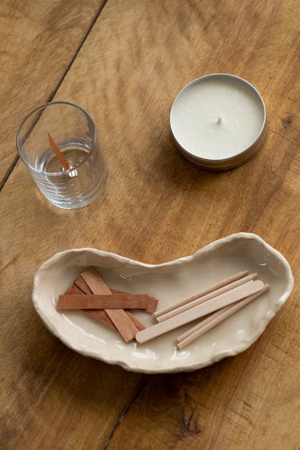 Top view of a candle making setup with a wooden table and wicks.